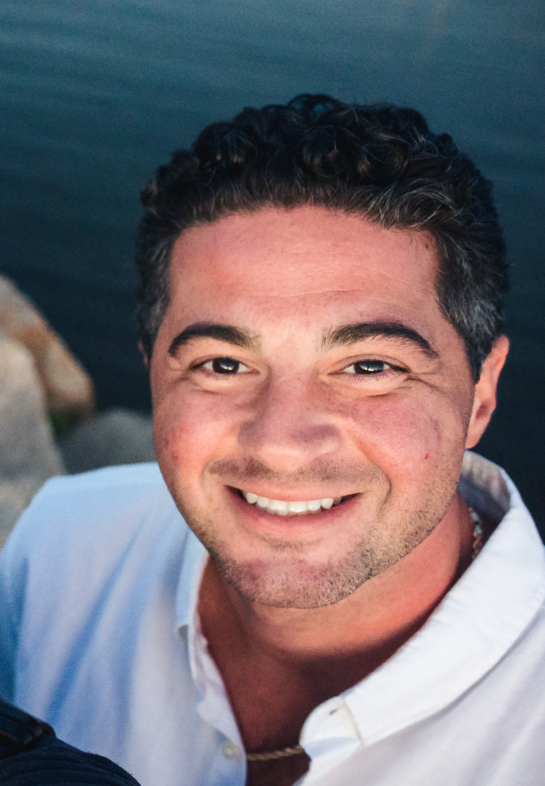 A smiling man in a white shirt and tie