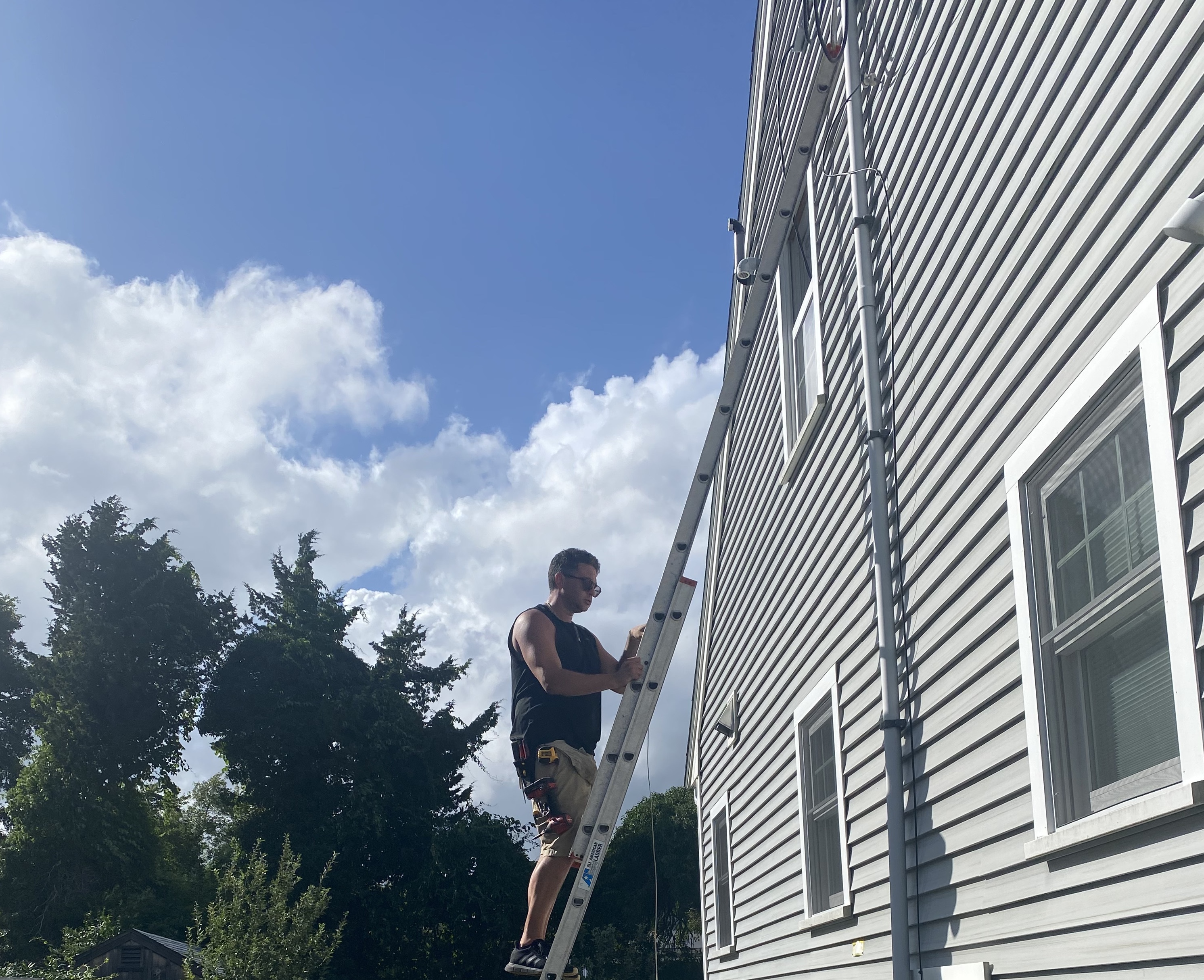 A man on a ladder painting the side of a house